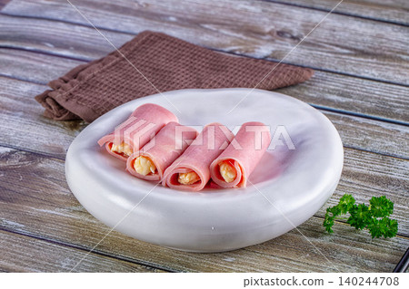 Ham and cheese rolls on white plate with parsley on wooden table Ham and cheese rolls on white plate with parsley on wooden table 140244708