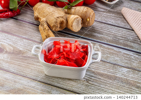 Sliced pickled ginger in white ceramic dish with fresh ginger roots on rustic wooden table Sliced pickled ginger in white ceramic dish with fresh ginger roots on rustic wooden table 140244713
