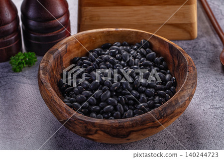Black beans in a wooden bowl with salt and pepper grinders on a gray stone surface Black beans in a wooden bowl with salt and pepper grinders on a gray stone surface 140244723