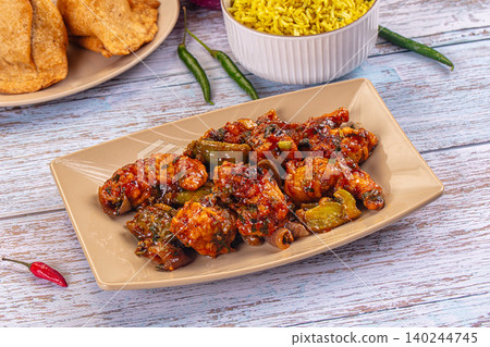 chilli chicken with yellow rice and papadums on wooden table 140244745