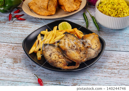 Fried Fish Steaks with Fries and Rice on Wooden Table 140244746
