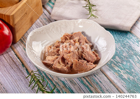 Flaked canned tuna in a white ceramic bowl with fresh rosemary on a rustic wooden table Flaked canned tuna in a white ceramic bowl with fresh rosemary on a rustic wooden table 140244763