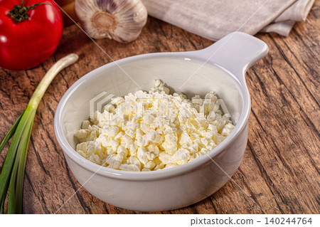 Bowl of fresh cottage cheese with tomato, garlic and spring onion on a wooden table Bowl of fresh cottage cheese with tomato, garlic and spring onion on a wooden table 140244764