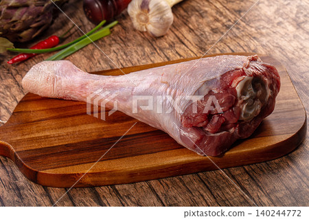 Raw turkey leg on wooden cutting board with vegetables Raw turkey leg on wooden cutting board with vegetables 140244772