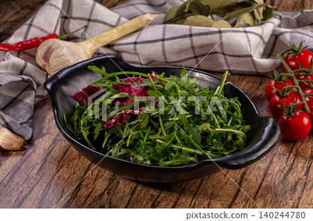 Fresh Mixed Salad Greens in Black Bowl on Rustic Wooden Table with Vegetables Fresh Mixed Salad Greens in Black Bowl on Rustic Wooden Table with Vegetables 140244780