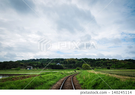 The early summer countryside and the Kominato Railway tracks spread out under a cloudy sky. The early summer countryside and the Kominato Railway tracks spread out under a cloudy sky. 140245114