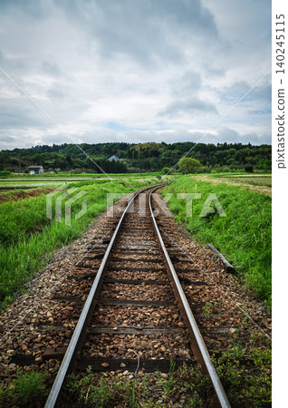The early summer countryside and the Kominato Railway tracks spread out under a cloudy sky. The early summer countryside and the Kominato Railway tracks spread out under a cloudy sky. 140245115