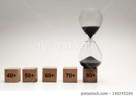 Hourglass beside age blocks from 40 to 80, aging population, life stages and time passing 140245284
