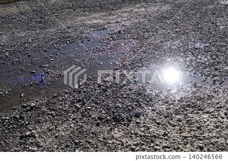 A scene of a gravel path along the Edogawa River after a winter rain, with puddles in the water. A scene of a gravel path along the Edogawa River after a winter rain, with puddles in the water. 140246566