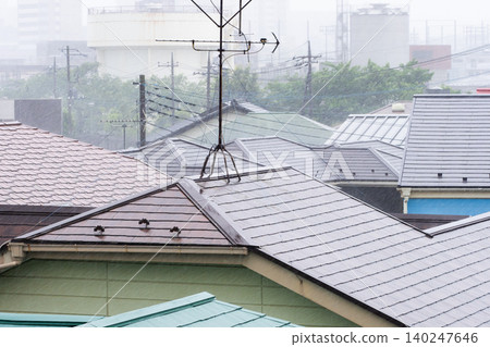 瓢潑大雨傾瀉在房屋的屋頂上。 瓢潑大雨傾瀉在房屋的屋頂上。 140247646