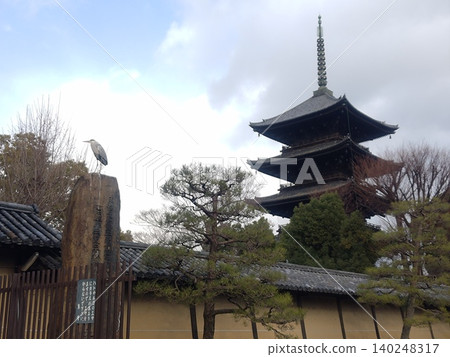 A heron standing beside a five-story pagoda and a stone monument. 140248317