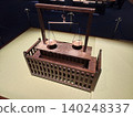 A museum exhibiting a wooden balance scale model. 140248337