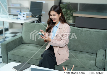 Business woman using computer working online, doing searching, taking notes looking at smartphone at work. Business woman using computer working online, doing searching, taking notes looking at smartphone at work. 140248605
