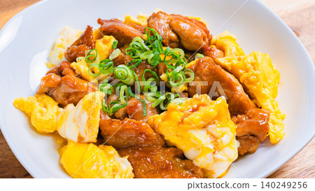 A photo of a Japanese-style dish of teriyaki chicken and egg stir-fried in a sweet and savory sauce. 140249256