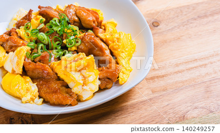A photo of a Japanese-style dish of teriyaki chicken and egg stir-fried in a sweet and savory sauce. 140249257