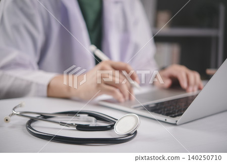 Doctor working on laptop computer with stethoscope on white table. Medical technology, online consultation, and healthcare business concept with copy space for text. Doctor working on laptop computer with stethoscope on white table. Medical technology, online consultation, and healthcare business concept with copy space for text. 140250710