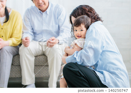 一家三代同堂:母親和祖父母在客廳和孩子玩耍。 一家三代同堂:母親和祖父母在客廳和孩子玩耍。 140250747
