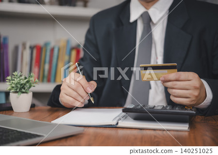 Credit card payment. Businessman holds card using calculator and notebook beside laptop in office, tracking finance, budget, expense, debt, banking, accounting for control. concept personal finance. 140251025