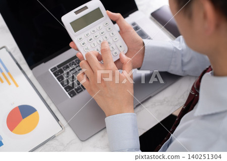 一位商人正在辦公桌前使用計算機。 一位商人正在辦公桌前使用計算機。 140251304