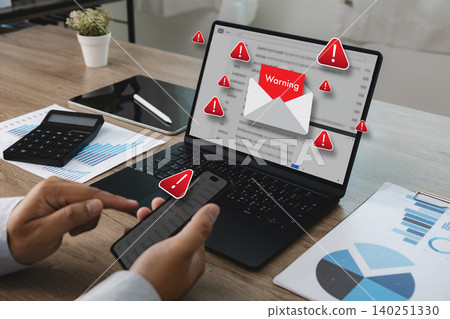 Laptop displaying phishing email warning notifications while person uses smartphone for scam detection, cybersecurity protection, suspicious message analysis, and online security management. 140251330