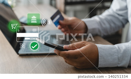 Person using a smartphone, credit card and laptop for online banking money transfer, digital payment authorization and secure financial transaction process in a modern cashless banking environment. Person using a smartphone, credit card and laptop for online banking money transfer, digital payment authorization and secure financial transaction process in a modern cashless banking environment. 140251334