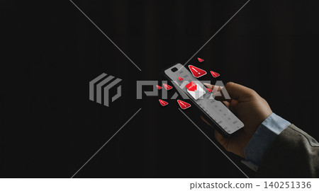 Hand holding smartphone with spam warning icons and fake text message alert on dark background, representing SMS phishing attack, online fraud risk, mobile scam, and cyber security protection. Hand holding smartphone with spam warning icons and fake text message alert on dark background, representing SMS phishing attack, online fraud risk, mobile scam, and cyber security protection. 140251336