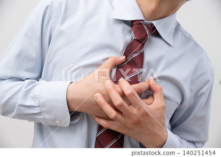 A businessman clutching his chest in pain against a white background. A businessman clutching his chest in pain against a white background. 140251454
