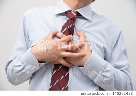 A businessman clutching his chest in pain against a white background. A businessman clutching his chest in pain against a white background. 140251458