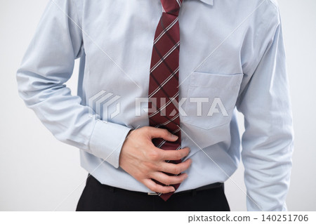 A businessman clutches his stomach due to abdominal pain. A businessman clutches his stomach due to abdominal pain. 140251706