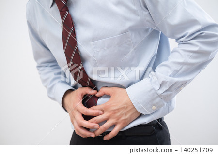 A businessman clutches his stomach due to abdominal pain. A businessman clutches his stomach due to abdominal pain. 140251709