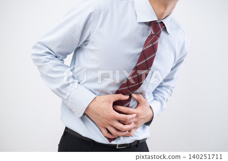 A businessman clutches his stomach due to abdominal pain. A businessman clutches his stomach due to abdominal pain. 140251711