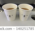 Hot drinks and polar bear-designed cups lined up on the in-flight tray table. 140251785