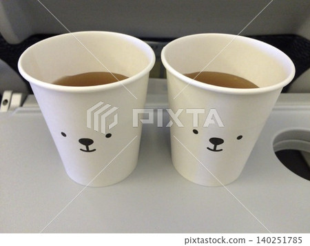 Hot drinks and polar bear-designed cups lined up on the in-flight tray table. Hot drinks and polar bear-designed cups lined up on the in-flight tray table. 140251785
