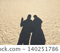 Two shadows, nestled close together, stretch across the beach. 140251786