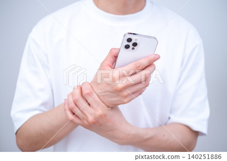 A man holding a smartphone with wrist pain A man holding a smartphone with wrist pain 140251886