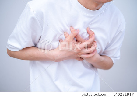 A man clutching his chest in pain against a white background. A man clutching his chest in pain against a white background. 140251917