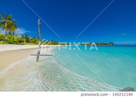 Woven hammock strung between leaning palms on a sugar white shore. Turquoise lagoon shimmering beyond swaying fronds. Dreamy tropical hideaway built for lazy afternoons. Idyllic Maldives beach Woven hammock strung between leaning palms on a sugar white shore. Turquoise lagoon shimmering beyond swaying fronds. Dreamy tropical hideaway built for lazy afternoons. Idyllic Maldives beach 140252190