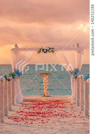 Rose petals scattered along the aisle toward a sunset wedding arch. Vertical view of a romantic ceremony glowing at dusk. Intimate beachfront altar framed by warm golden light. Dreamy destination Rose petals scattered along the aisle toward a sunset wedding arch. Vertical view of a romantic ceremony glowing at dusk. Intimate beachfront altar framed by warm golden light. Dreamy destination 140252198