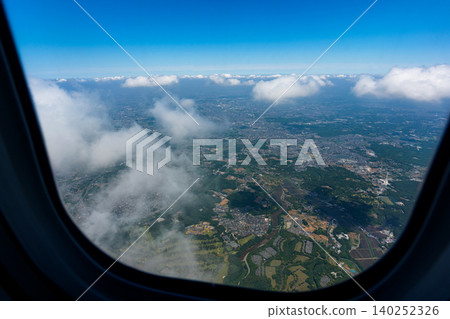 從飛機舷窗看到的關東平原的居民區和雲層:日本的鳥瞰圖。 從飛機舷窗看到的關東平原的居民區和雲層:日本的鳥瞰圖。 140252326