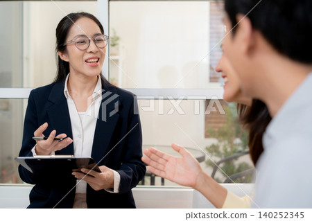 Counselor writing on clipboard during consultation, asian couple holding hands and sitting on sofa. Counselor writing on clipboard during consultation, asian couple holding hands and sitting on sofa. 140252345