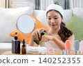 Beautiful young asian woman applying lotion herb on hands looking mirror at home. 140252355