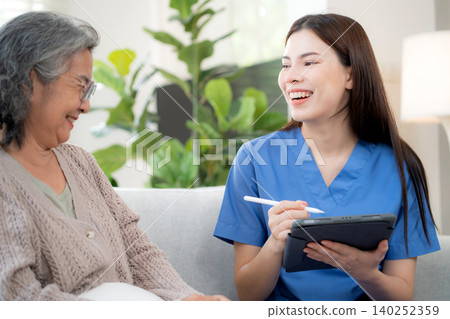 Asian woman caregiver using digital tablet for senior patient consultation. 140252359