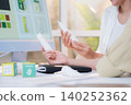 Two asian woman discussing cosmetic tube packaging sitting at modern home office. 140252362