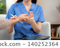 Young nurse caregiver woman examining elderly while holding arm for pulse record on tablet. 140252364