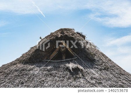 The top of a traditional thatched roof stands out against the blue sky. The top of a traditional thatched roof stands out against the blue sky. 140253678