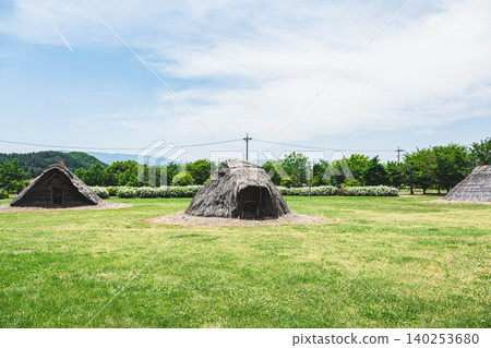 A reconstructed pit dwelling from the Heian period and the Hiraide archaeological site under a clear blue sky. A reconstructed pit dwelling from the Heian period and the Hiraide archaeological site under a clear blue sky. 140253680