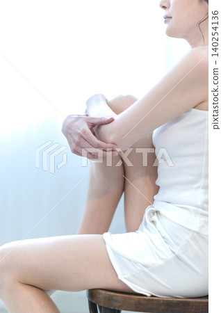 A woman sitting on a chair with one leg up A woman sitting on a chair with one leg up 140254136