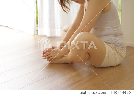 A woman performing hip stretches while sitting on the floor. 140254490