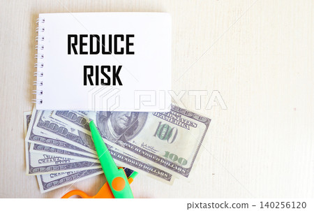 The concept of risk management. There is a notebook with the inscription "Reduce risk" and dollars The concept of risk management. There is a notebook with the inscription "Reduce risk" and dollars 140256120