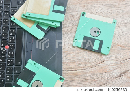 floppy disk old technology for saving data arranging with laptop computer on table floppy disk old technology for saving data arranging with laptop computer on table 140256883